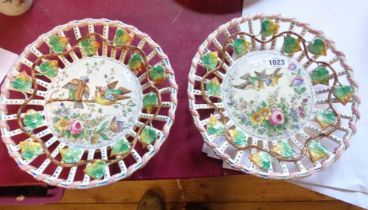 A pair of Lille French faience plates with pierced rims and central hand painted panels, depicting