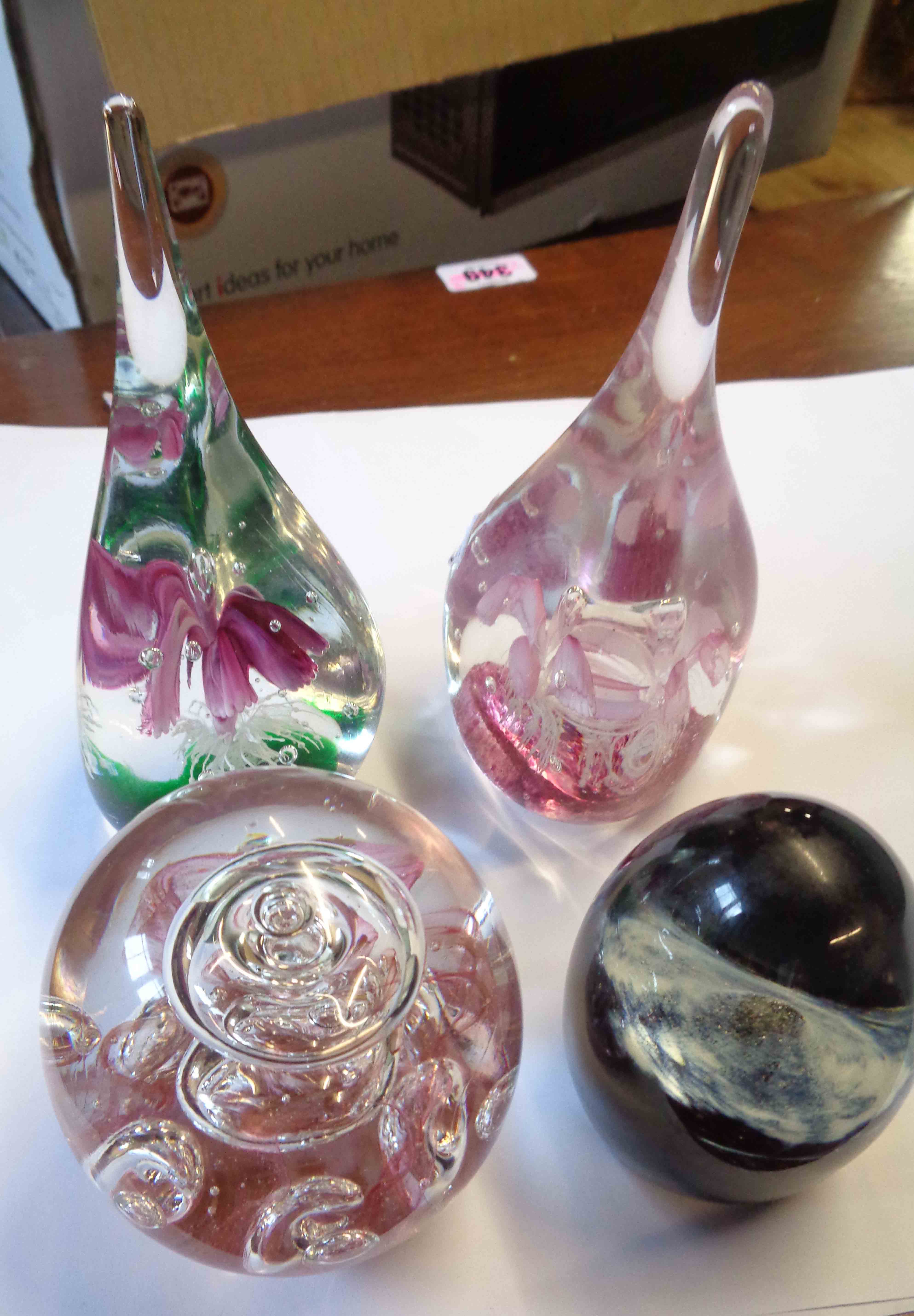 A box containing four glass paperweights