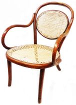 A vintage Thonet bentwood elbow chair with rattan back and seat panels