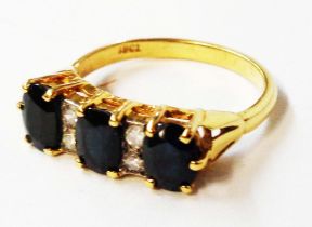 A marked 18ct. yellow metal ring, set with three oval green/dark blue sapphires interspersed with