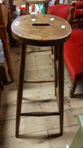 An old stained beech bar stool with oval seat, set on tapered supports