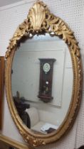 A reproduction giltwood framed oval wall mirror with decorative shell pattern pediment - 1.3m X 1.