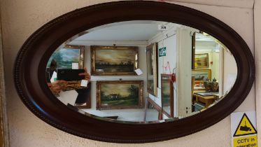 A 1920's mahogany framed bevelled oval wall mirror with beaded border