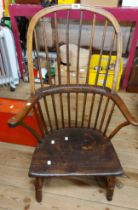 An antique elm Windsor hoop stick back elbow chair with moulded solid seat, set on reduced turned