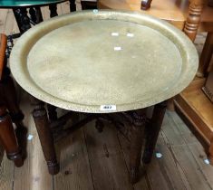 A 59cm diameter Benares brass tray-top table with peacock and other decoration, set on a carved