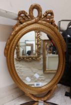 A small ornate gilt framed oval wall mirror - sold with a convex mirror plate taped to a backboard