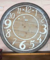 A large decorative wooden clock face with white painted cutout numbers - no hands