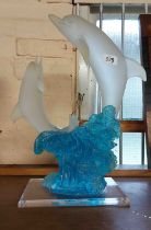 A perspex and resin figurine, depicting a pair of dolphins leaping from the waves