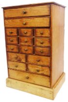 A 29.5cm pine miniature chest with an array of sixteen drawers, set on plinth base