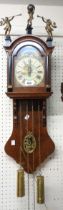 A reproduction Dutch ornate polished oak cased wall clock with decorative dial, date aperture and