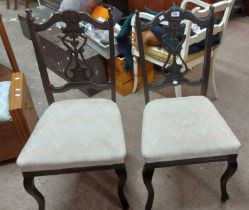 A pair of late Victorian ebonised framed standard chairs with pierced splats and later upholstered