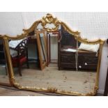 A large ornate reproduction gilt framed wall mirror with shaped plate and decorative border