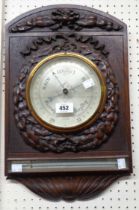 An early 20th Century carved oak framed decorative wall barometer with silvered dial marked for