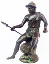 An old bronze figure, depicting a classical man holding a spear seated upon a fountain head