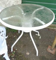 A modern circular garden table with frosted glass top, set on a white painted metal base