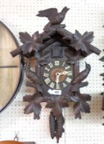 An old Black Forest cuckoo wall clock with applied bird and foliate decoration, twin weight driven