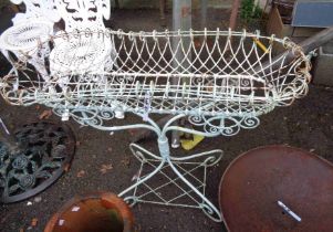 An antique style painted wirework plant stand with ornate pierced sides, set on quadruple scroll