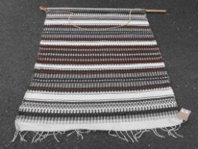 A North African handmade wool rug with striped design - mounted on a pole as a wall hanging - 1.7m X