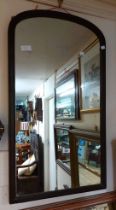 An early 20th Century stained wood framed wall mirror with arched plate