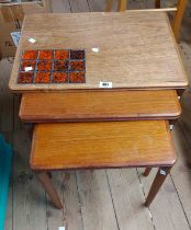A nest of three retro teak tea tables with part tiled inserts to largest table, set on simple turned