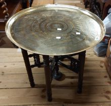 A 57.5cm diameter decorative Benares brass tray topped table, set on a typical stained wood