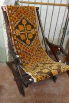 An early 20th Century stained wood framed folding chair with slung upholstery