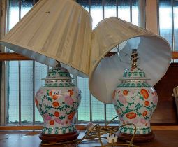 A pair of modern Chinese porcelain table lamps of lidded jar form, both set on wooden bases - sold