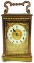 A late 19th Century brass and bevelled glass cased carriage clock with decorative engraved dial