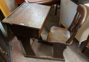 An old oak lift-top school desk, set on standard ends with attached splat back chair