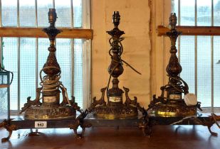 Three cast brass table lamps of Rococo form with inset ceramic panels set on marble bases