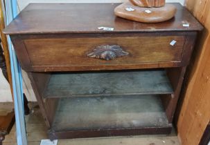 A 75cm antique oak side table with carved handle to single drawer and two open shelves under