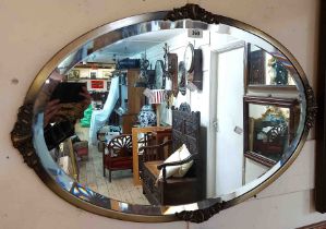 A vintage metal framed bevelled oval wall mirror with applied decoration - sold with a small