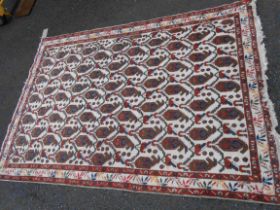 An eastern handmade wool rug with repeat stylised foliate motifs on cream ground within a narrow