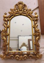 A reproduction Italian ornate giltwood framed Rococo style wall mirror with pierced pediment and