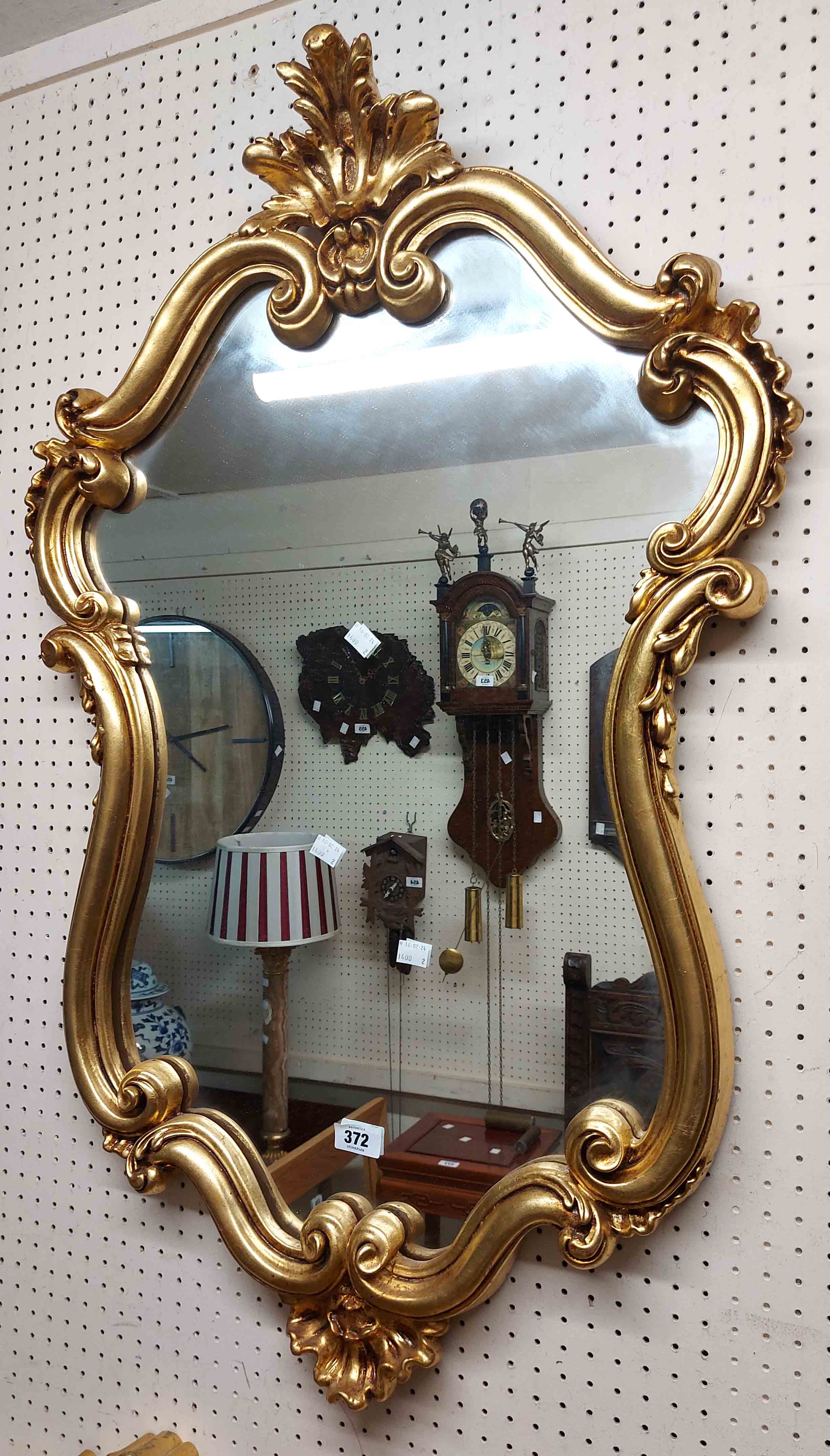 A reproduction gilt framed Rococo style wall mirror with shaped plate and decorative border