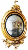A 65cm diameter Regency period giltwood framed convex wall mirror with recumbent doe form