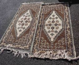 A pair of vintage Tunisian handmade wool rugs with central medallion within a border on brown ground