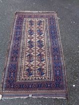 A vintage handmade wool rug with geometric repeat motifs within a wide border on grape coloured