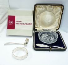 An antique English silver sifter ladle, a boxed cut glass butter dish with silver knife, a clasp