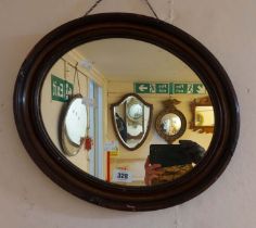 A small antique stained wood framed oval wall mirror
