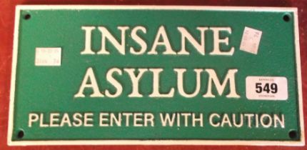 A modern cast iron 'Insane Asylum' sign with green and white painted finish