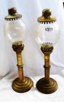 A pair of propelling candlesticks with glass dome covers in the form of an oil lamp