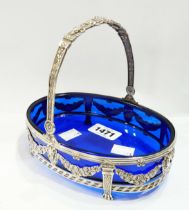 A Spanish silver bon bon dish with 16.5cm oval blue glass liner, swing handle and embossed and