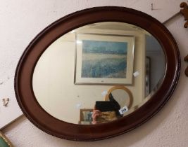 An early 20th Century mahogany framed bevelled oval wall mirror with part beaded border