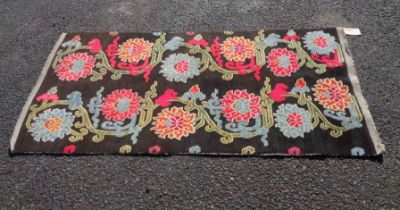 A vintage Tibetan Kahden handmade wool rug with two rows of polychrome floral scrolls on black