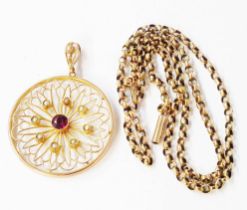 A 3.5cm diameter marked 9ct. yellow metal pierced pendant, set with central garnet and seed pearls -