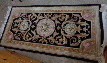 A modern Chinese handmade washed wool rug with roundel and scroll decoration within a shaped