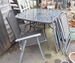 A modern glass topped garden table - sold with a set of four folding chairs to match