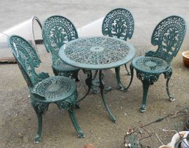 A modern green painted ornate cast aluminium patio table with pierced decoration and four chairs -