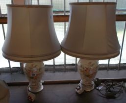 A pair of ceramic lamps with floral decoration on a cream ground